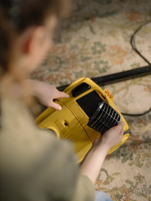 A child dressed in casual clothing and white sneakers is vacuuming an oriental-style area rug with a patterned floral design in a room with soft lighting. The vacuum cleaner, which appears to be a canister model with a yellow body and black hose, is moving across the plush, textured surface. The room features a wooden floor partially visible beneath the rug, and the surrounding furniture includes a glimpse of a leather armchair or couch in the corner. The scene demonstrates surface cleaning as part of a domestic cleaning process, with Hounslow Cleaners' professional services focusing on maintaining hygiene and deep cleaning. The image emphasizes thorough vacuuming to remove dust and improve cleanliness on woven, fibrous materials.